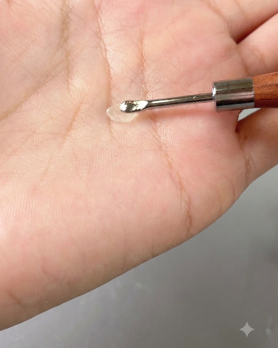A small dollop of transparent gel resting on a hand tool against the palm.