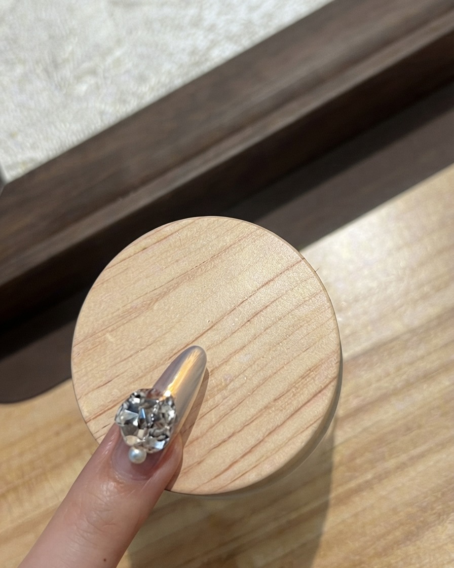 Close-up of an index fingernail decorated with a curved row of tiny sparkling rhinestones.