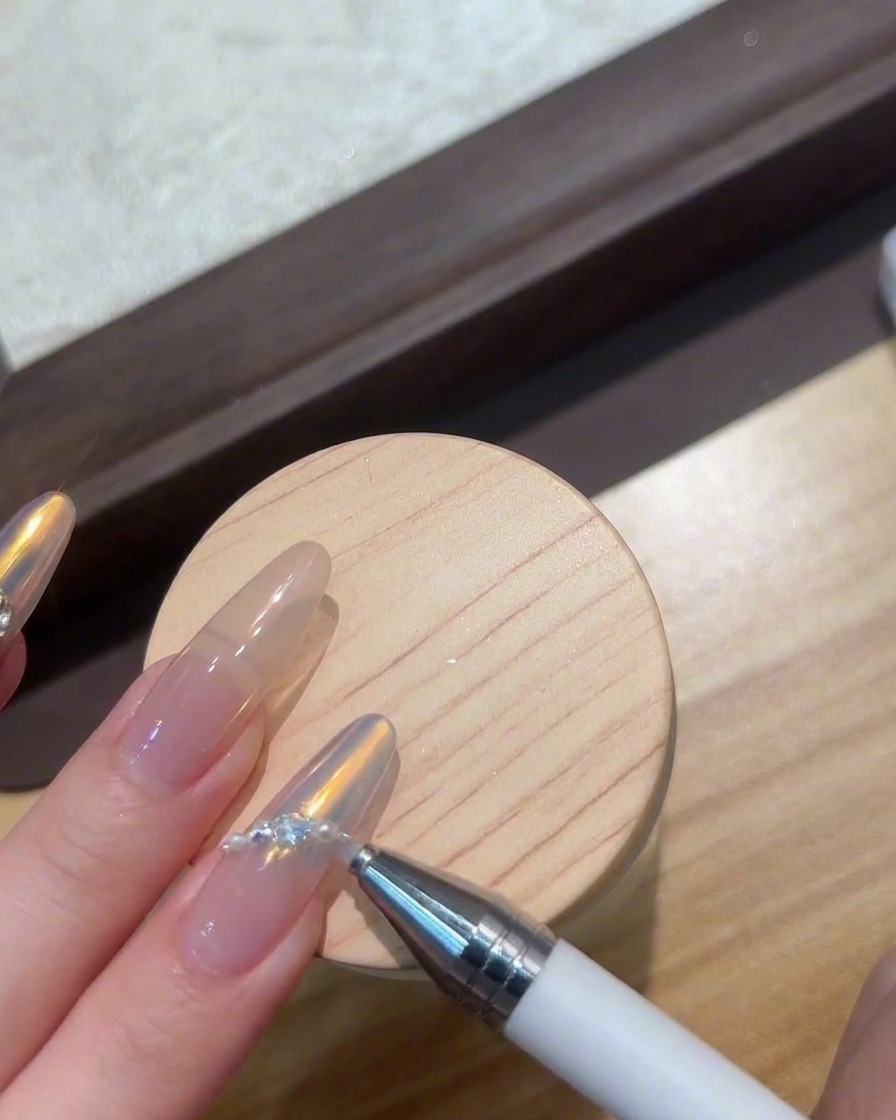 Fingers placed under a compact UV/LED lamp curing nail art gems.