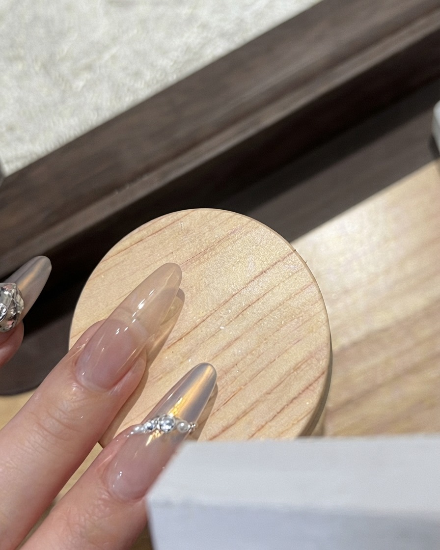 A nail technician placing a white frosted butterfly charm onto a glossy nail.