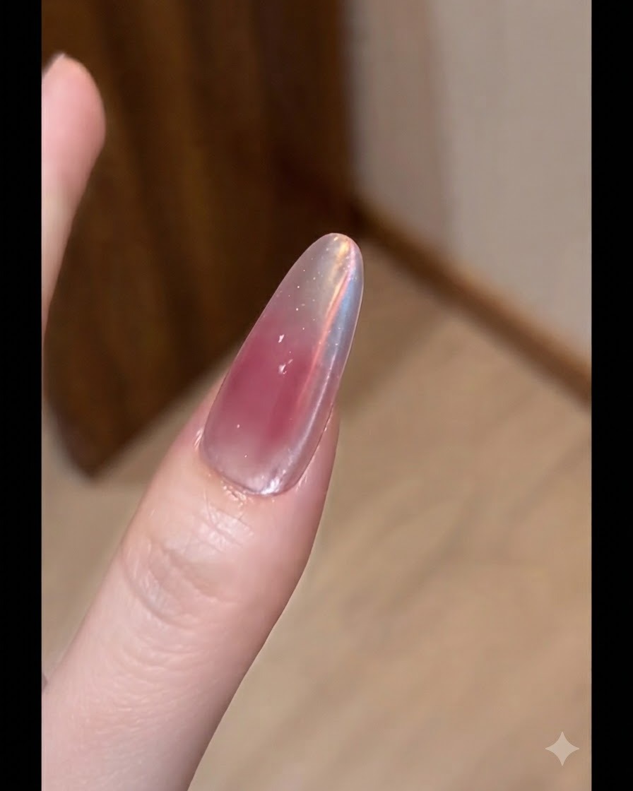 A flat brush applying a thin coat of nude color gel onto an extended nail.