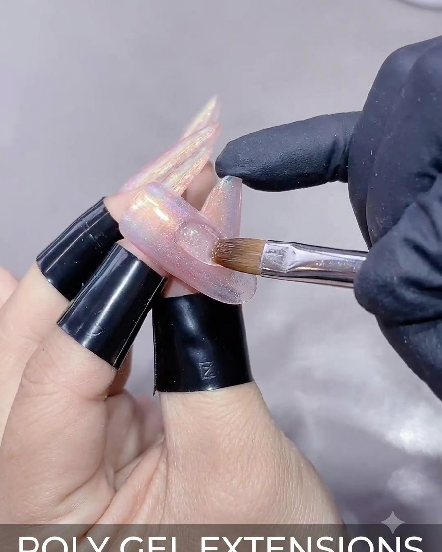 A close-up of a hand holding a magnetic wand over an extended nail to shape the cat-eye gel reflection.