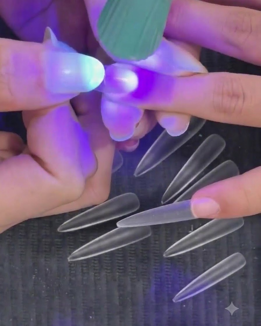 A hand holding a mini purple UV LED flashlight over a fingernail to cure a semi-cured nail tip.