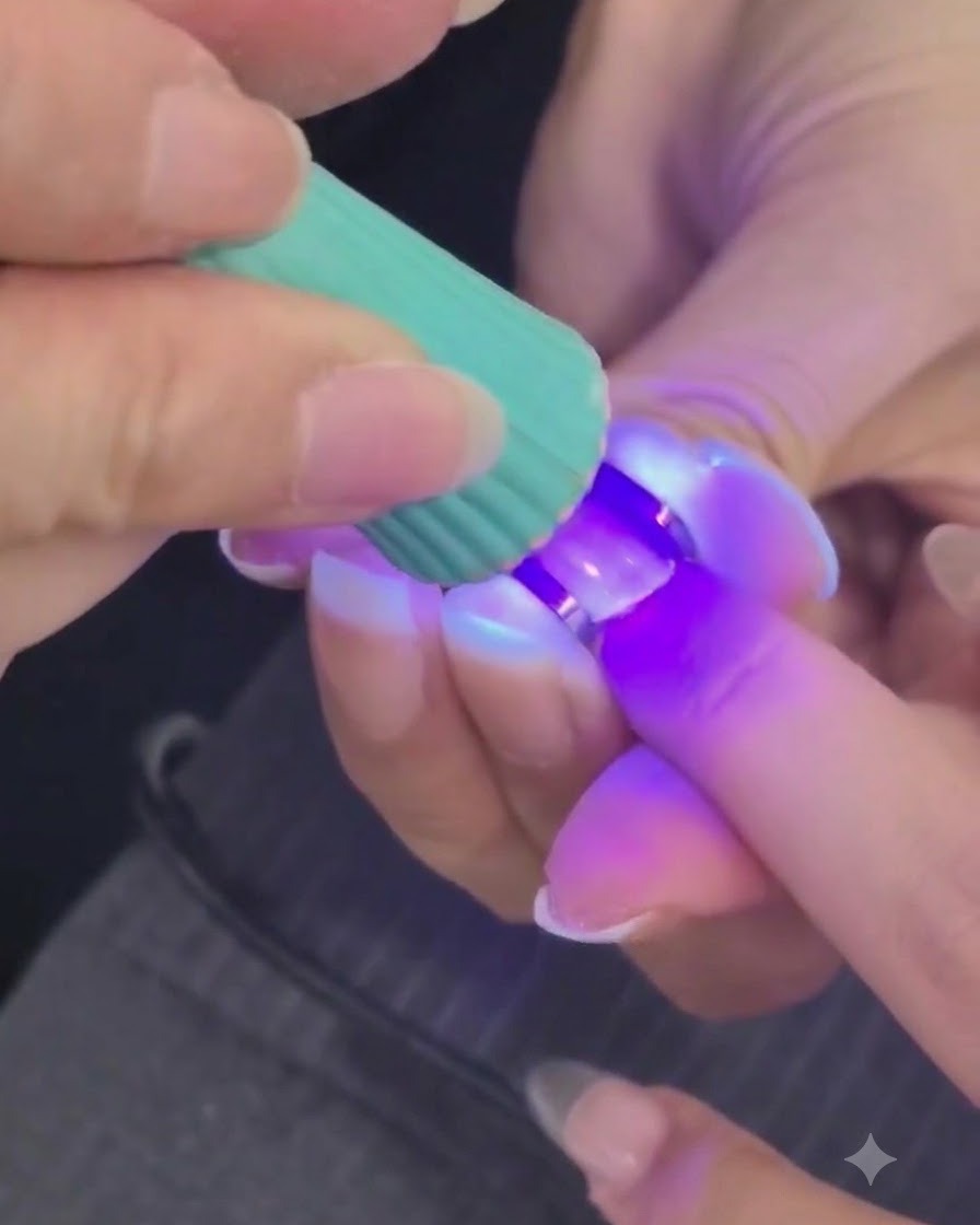 A mini UV or LED lamp curing a structured nail gel layer on a finger.