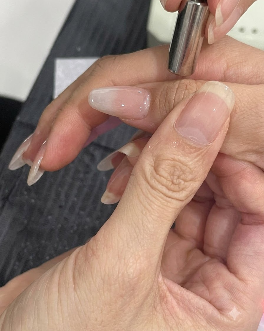 A small magnetic tool held close to the side of a manicured nail to shift cat-eye shimmer particles.