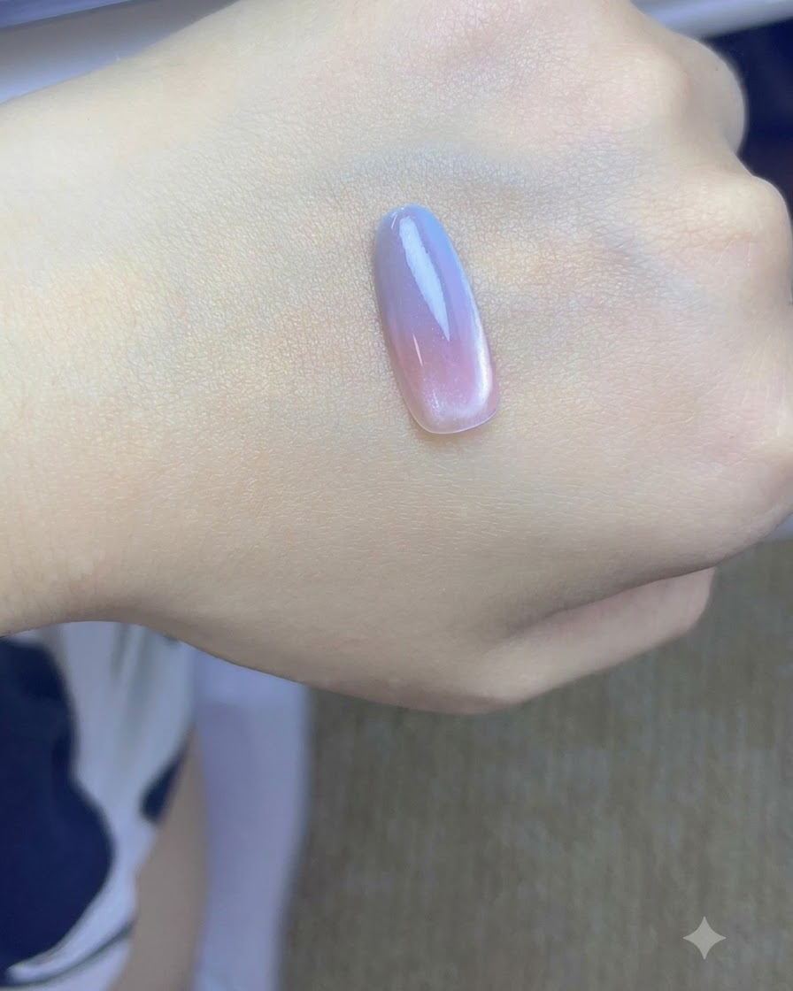 A nail tip with pink and blue gradient layers curing under a UV/LED lamp.