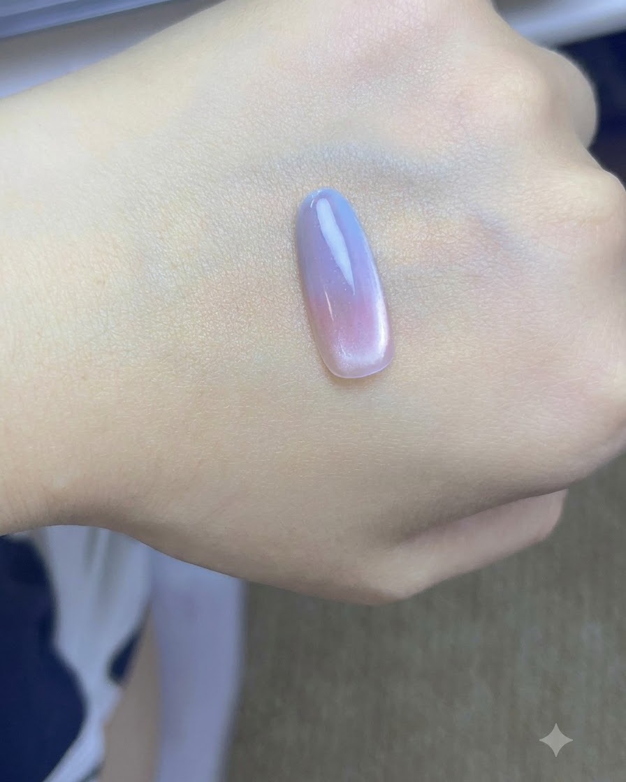 A brush patting a second layer of blue gel onto the tip of the nail on a hand.
