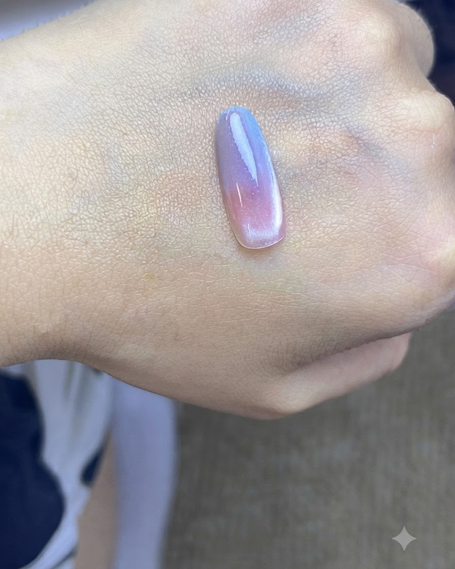 A nail tip placed under a UV curing lamp after applying the second blue gradient layer.
