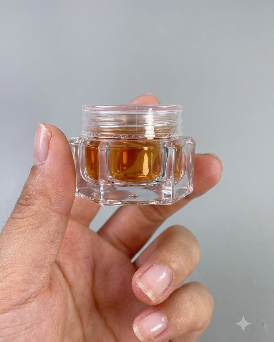 A small jar of amber-colored high-transparency glass gel No. 9 held in a hand.