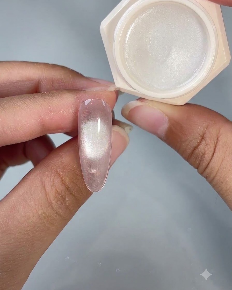 A finished cat-eye gel nail shown next to its open product jar under studio lighting.