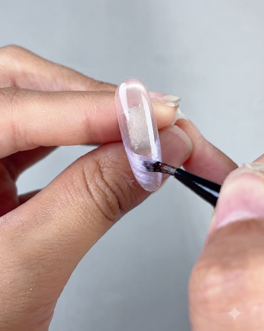 A fine art liner brush drawing a pearlescent French tip line on a clear sculpted nail extension.