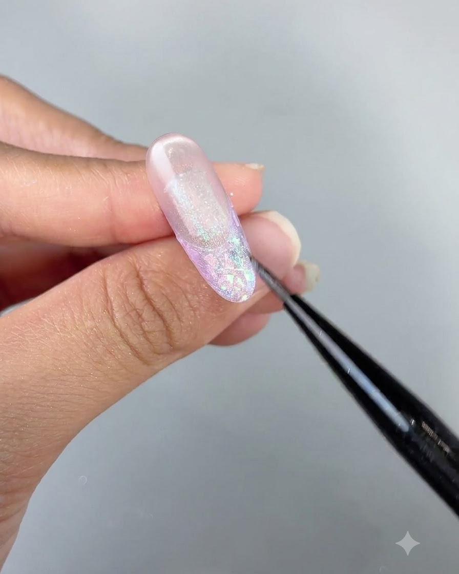 A detailed close-up of a brush refining cat eye gel details on a long, glossy nail design.