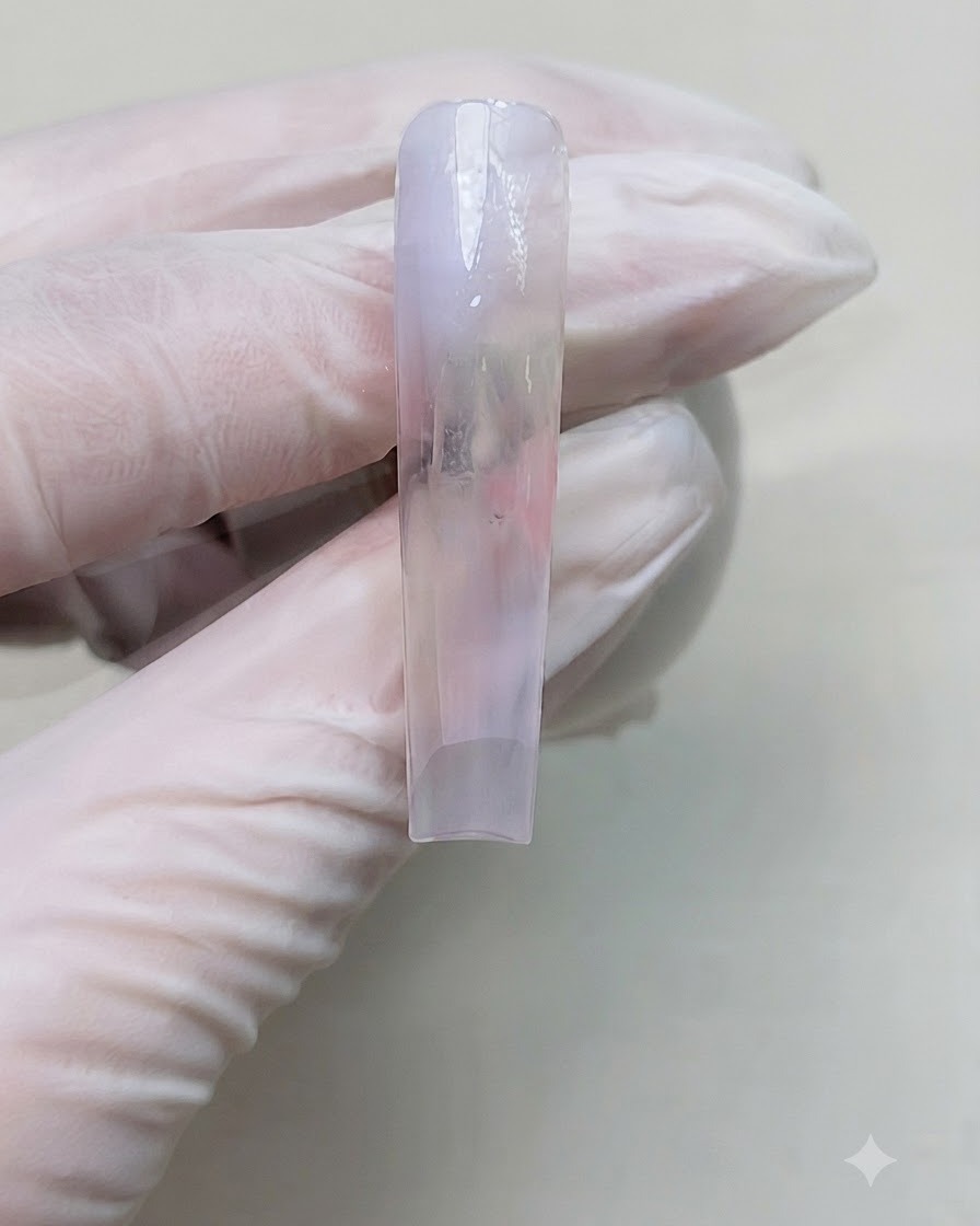A close-up view of a manicured nail after curing the gradient color layer under a portable nail lamp.