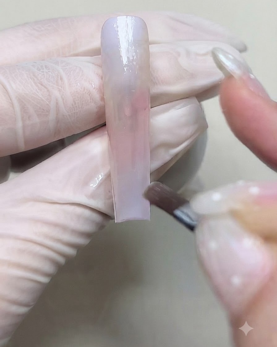A brush applying a second layer of color gel to deepen the gradient transition on the nail.