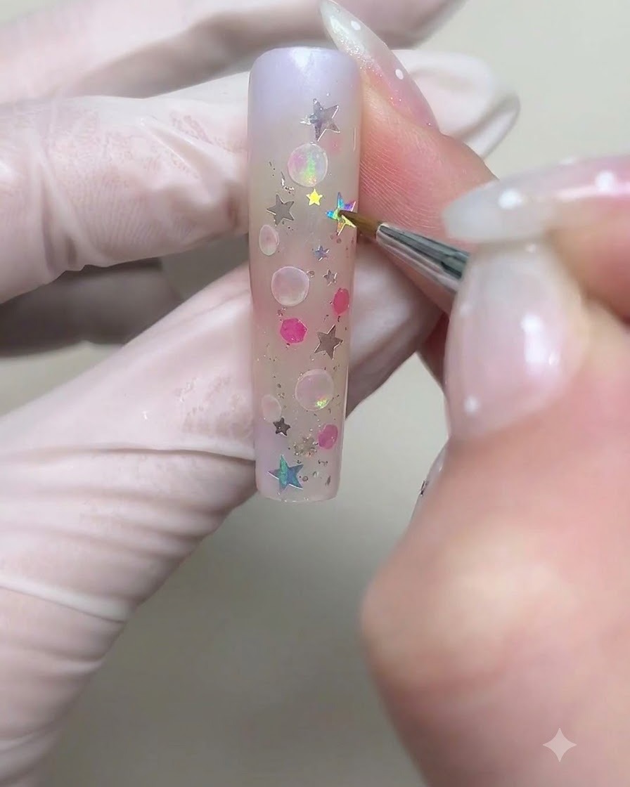 A fine brush drawing larger circular bubble outlines with white cream gel on the nail.