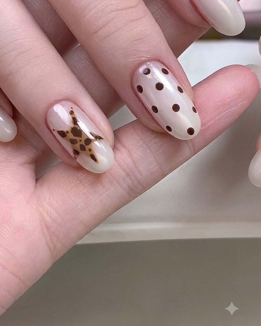 A close-up hand showing nails with detailed star and polka dot nail art designs.