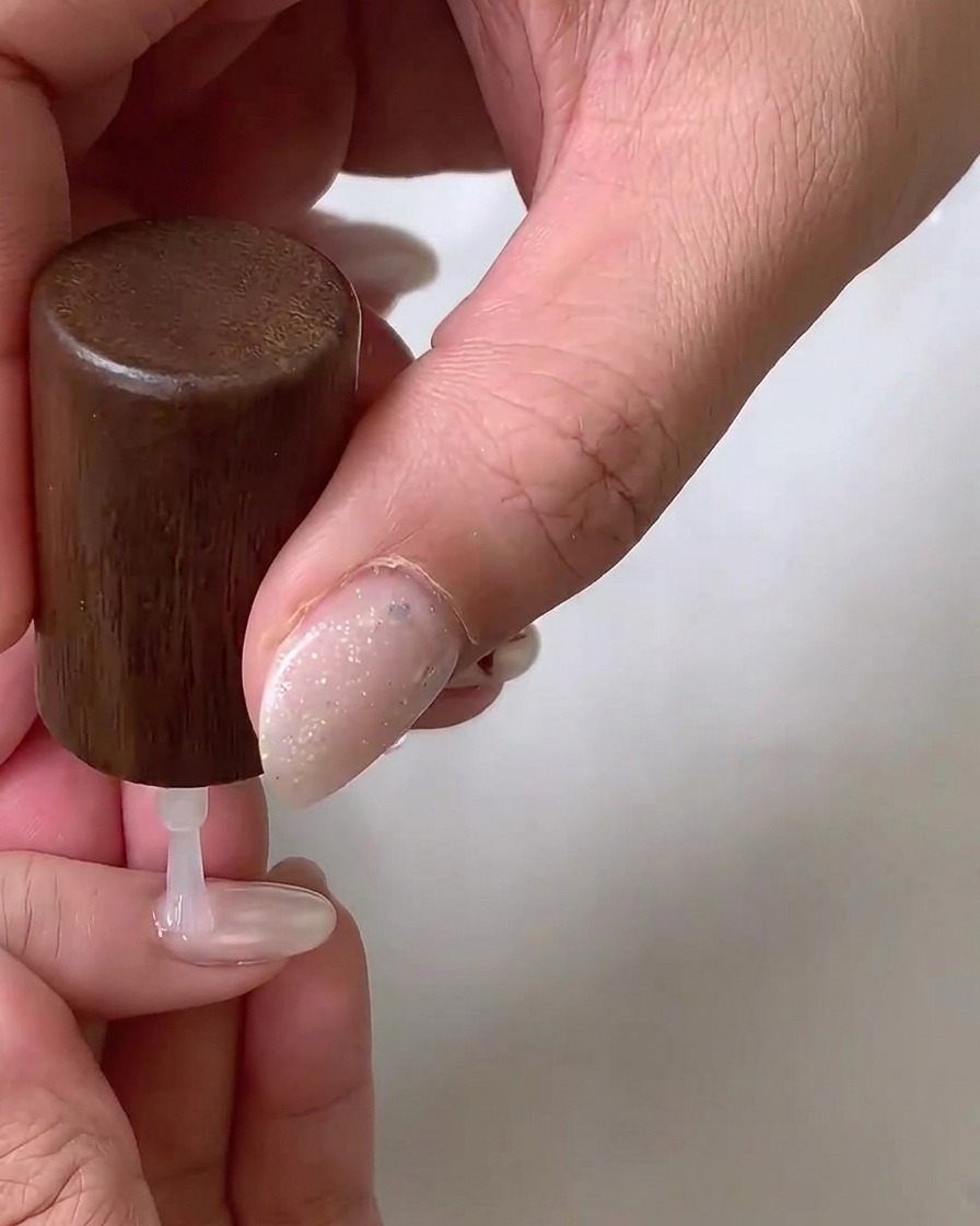 An e-file with a flame-shaped ceramic bit carefully refining the cuticle area of a natural nail.
