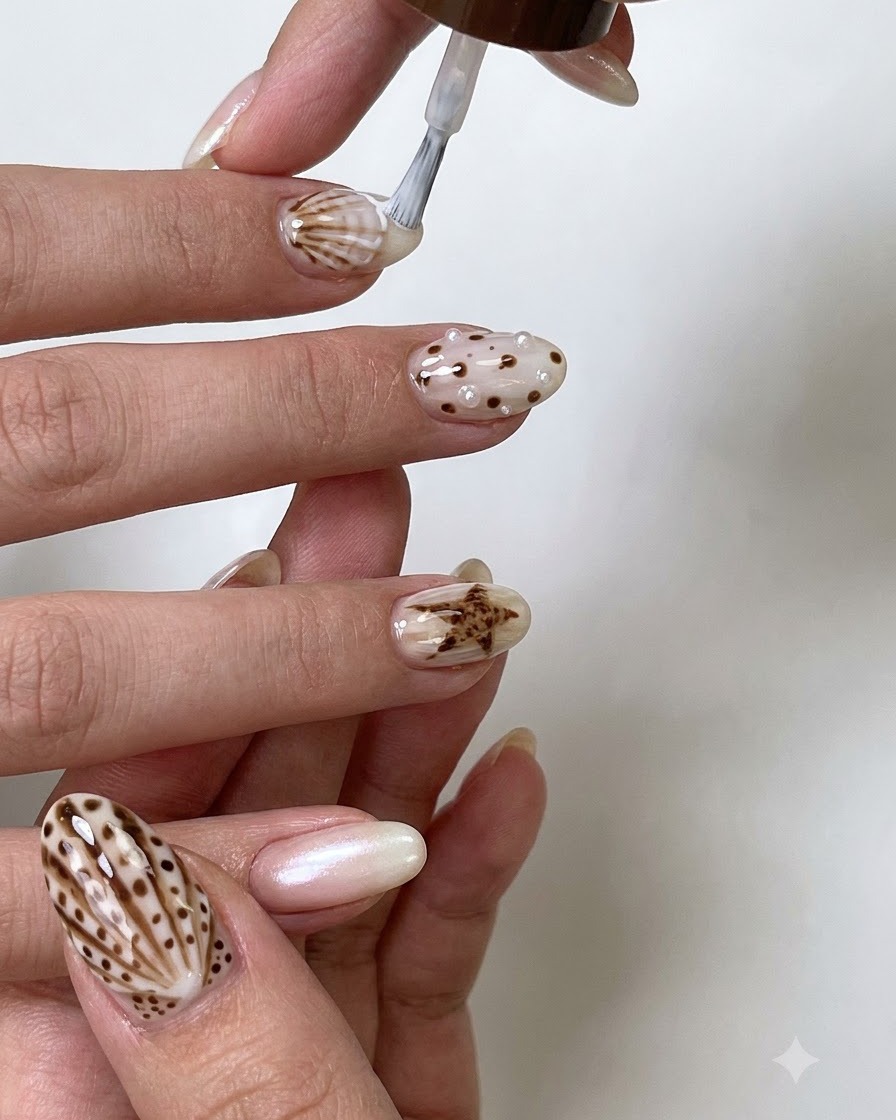 A fine liner brush drawing precise brown details and outlines on a decorated nail.
