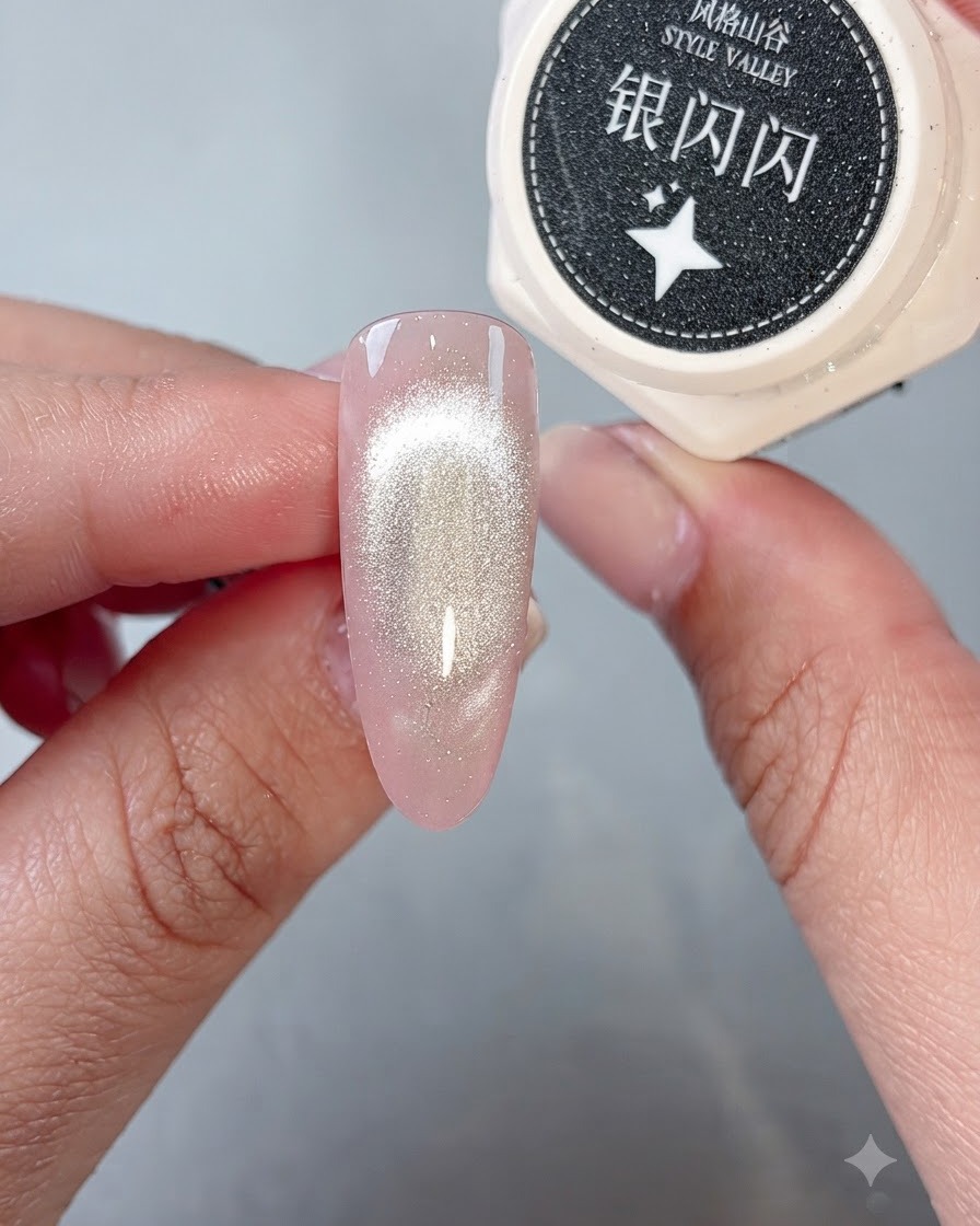 A brush placing sparkling silver glitter gel onto the tip of a cat-eye finished nail.
