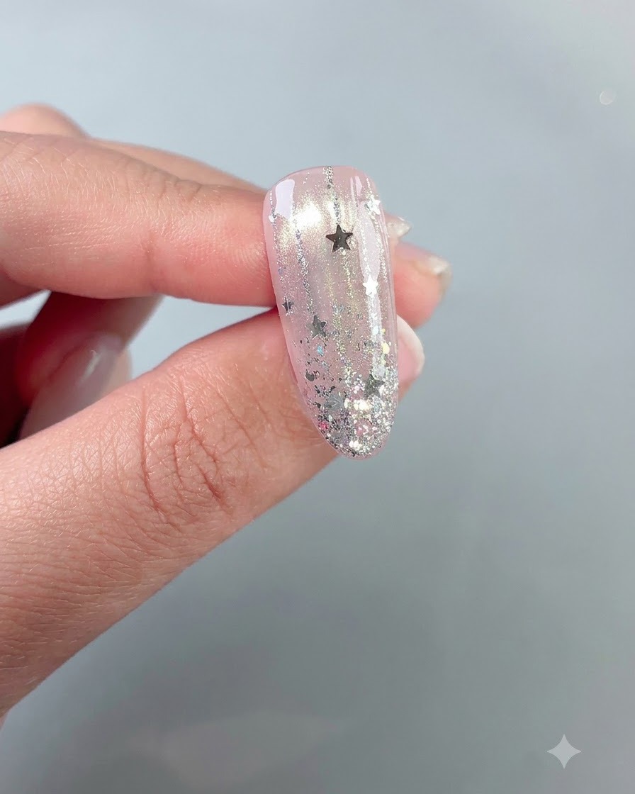 A finished glossy star-studded nail design held up against a neutral background.