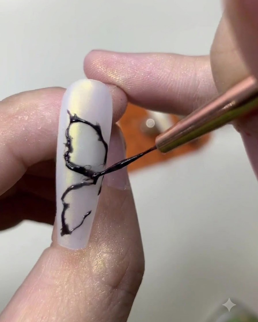 Close-up of a nail artist adding fine inner details to a painted black butterfly wing design.