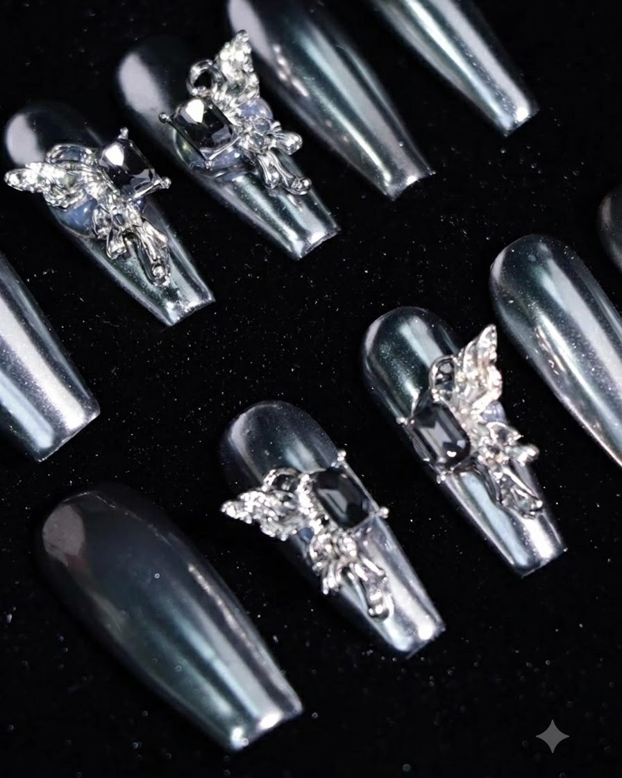 A close-up shot of a hand pressing a silver metallic press-on nail onto a natural fingernail.