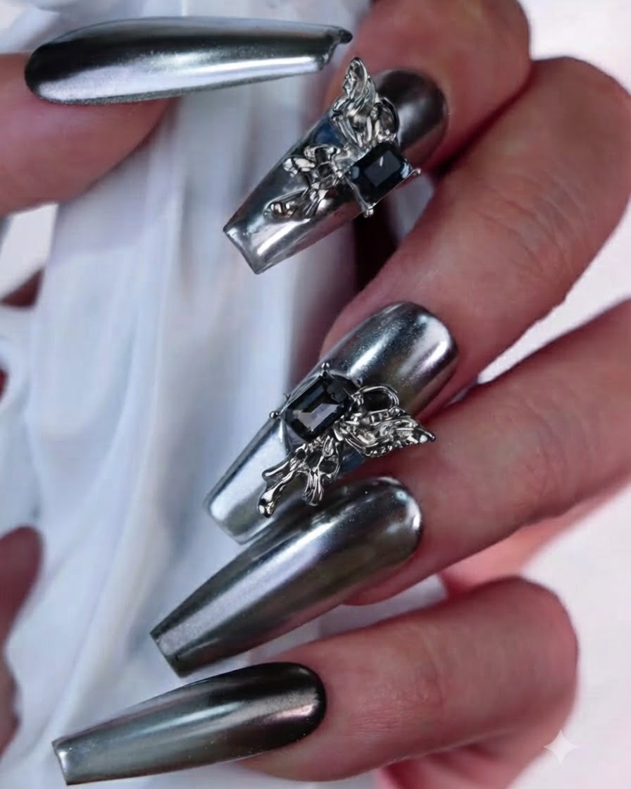 Macro view of a silver chrome artificial nail showcasing an ornate 3D butterfly embellishment and a dark rectangular gemstone.