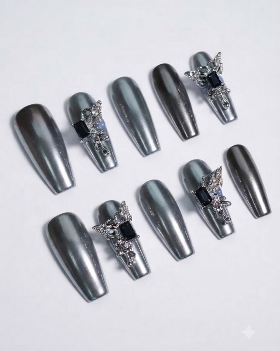 Detailed macro shot focusing on a dark gemstone centerpiece surrounded by sculpted silver butterfly wings on a chrome nail.