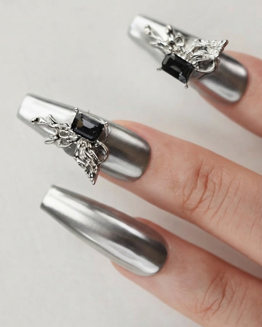 A close-up of a finger showing a silver chrome nail adorned with a detailed 3D butterfly charm and dark crystal.