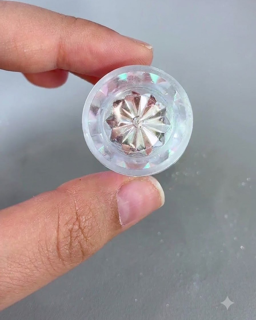 A jar of iridescent chrome powder held in a hand next to a prepped nail.