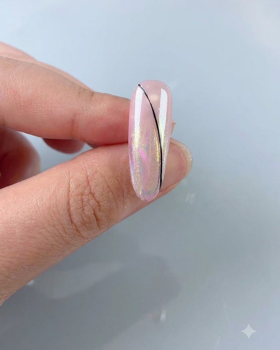 A fine liner brush drawing a delicate black curved line on an aurora pink nail.