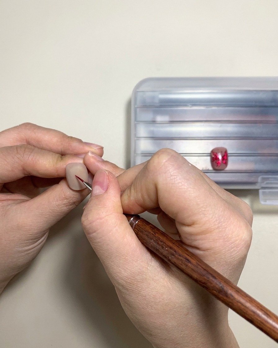A hand placing a finished gel nail design under a UV or LED curing lamp.
