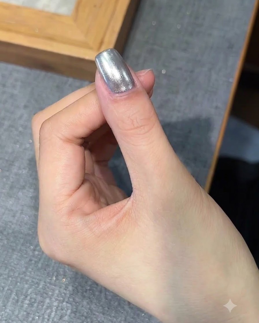 A brush applying a layer of base gel over the chrome-finished nail.