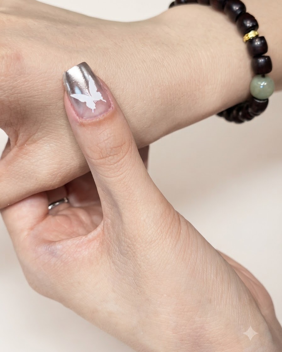 A manicured fingernail with a white butterfly design positioned under a UV or LED curing lamp.
