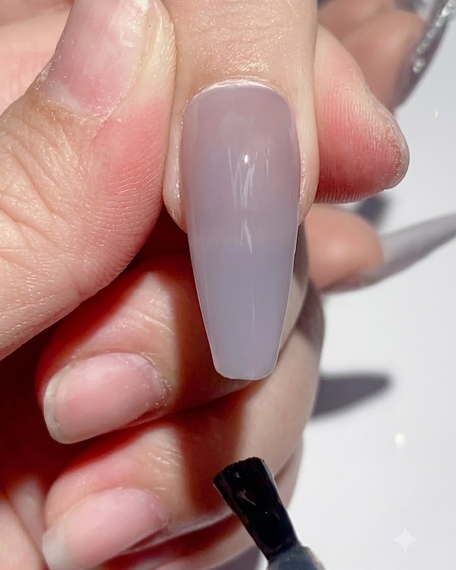 A hand placed under a UV LED nail lamp during the curing process.