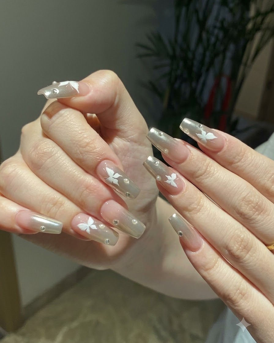 Two hands posed together displaying the complete silver chrome and butterfly nail art under warm indoor lighting.