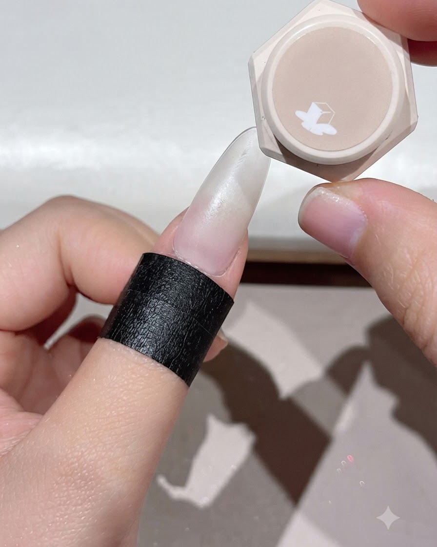 A finger placed under a UV or LED nail lamp to cure the applied gel layer.