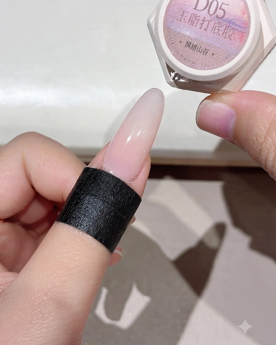 A cured nail showing an even pinkish base layer under lighting.