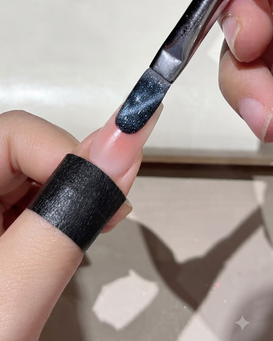 A brush applying dark blue cat eye gel onto the edge of a prepped nail.