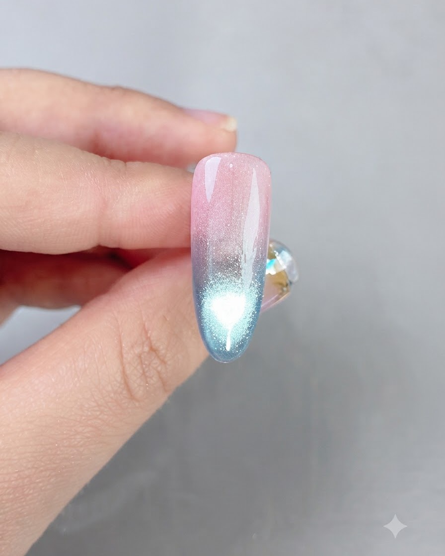 A finished pink and blue gradient nail showing a bright cat eye reflection line down the center.