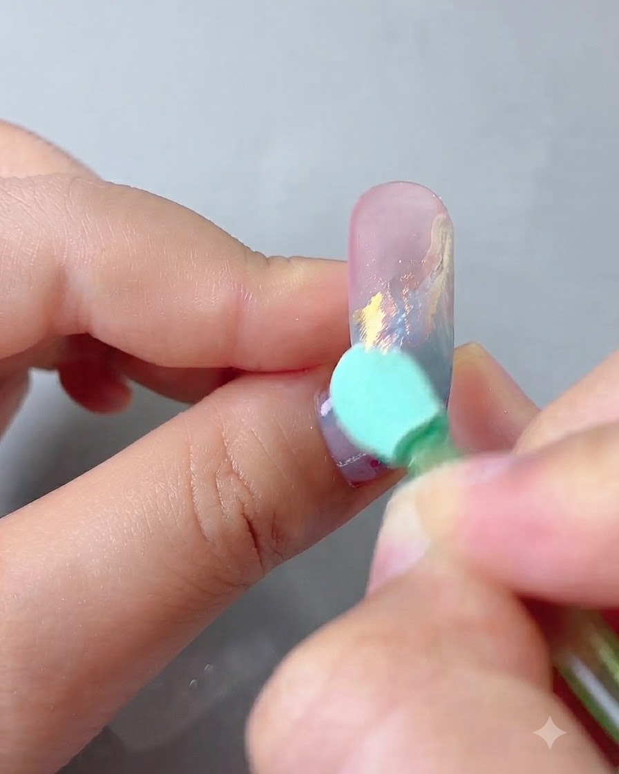 An applicator sponge rubbing aurora magic mirror powder onto the decorated nail surface.