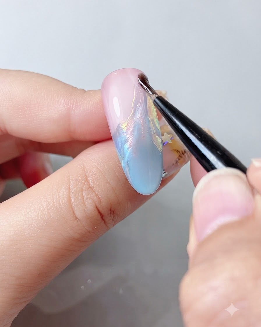 A fine nail brush applying a clear top coat over a shimmering multi-colored nail surface.