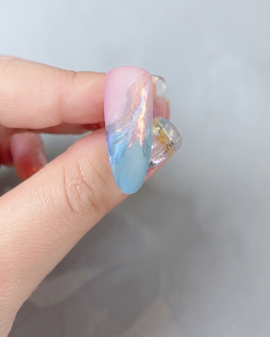 A close-up view of a nail surface receiving a light dusting of colored glitter powder.