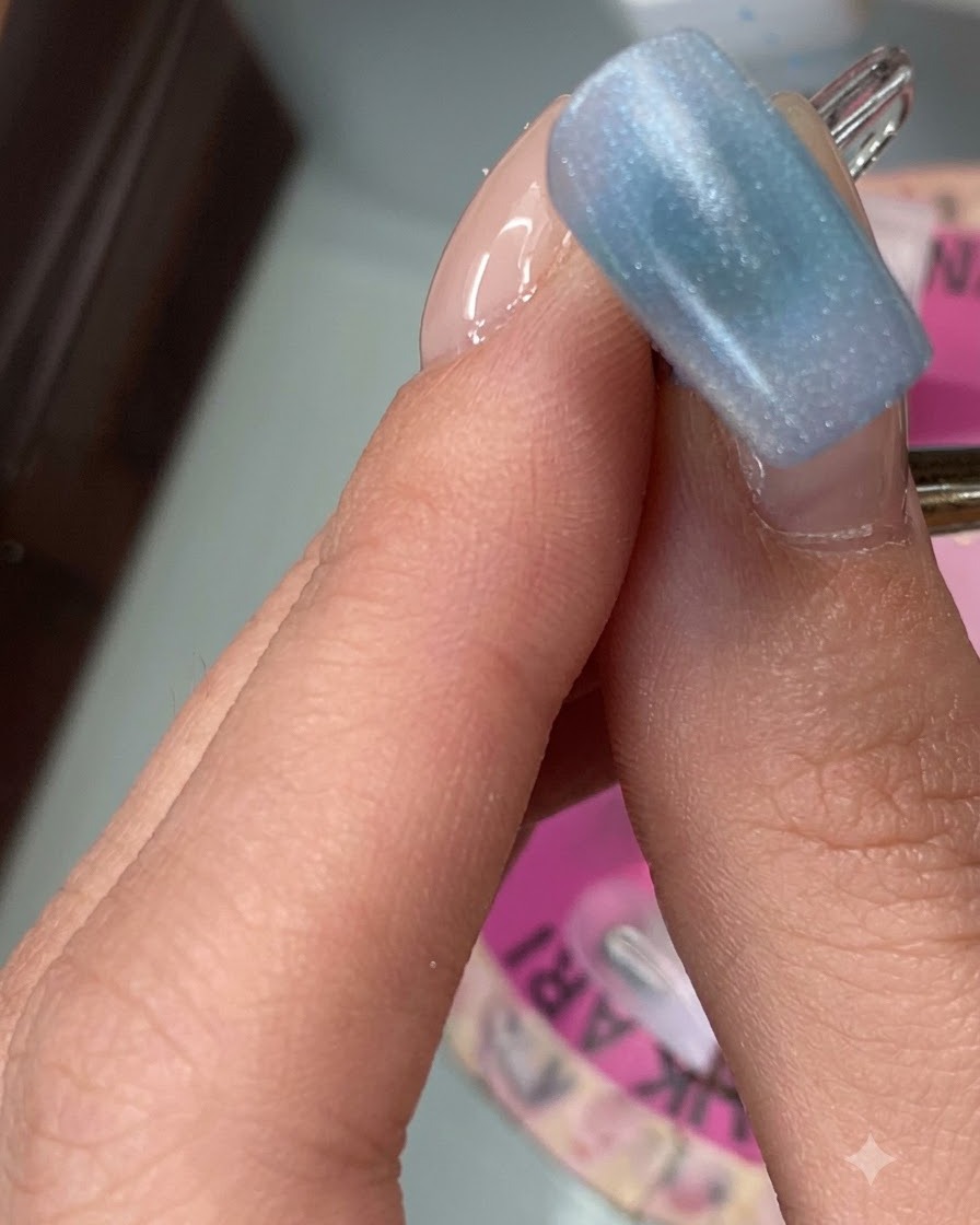 An index finger nail displaying a smooth first layer of black sesame colored gel.