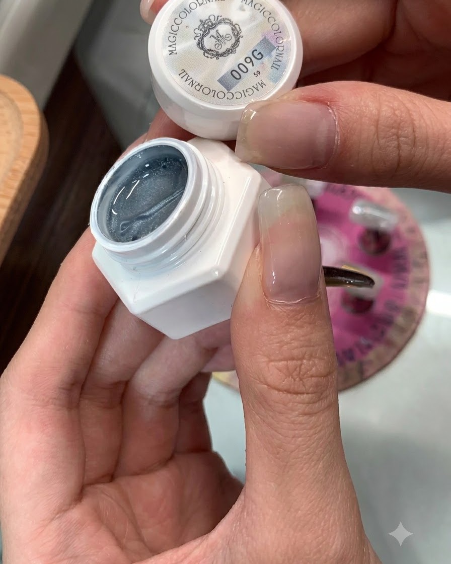 A jar of cats eye gel 009 next to a nail being prepared for application.