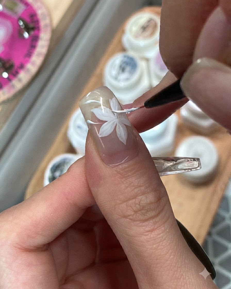 A fine brush blending adjacent pink and purple gel color blocks on a ring fingernail.