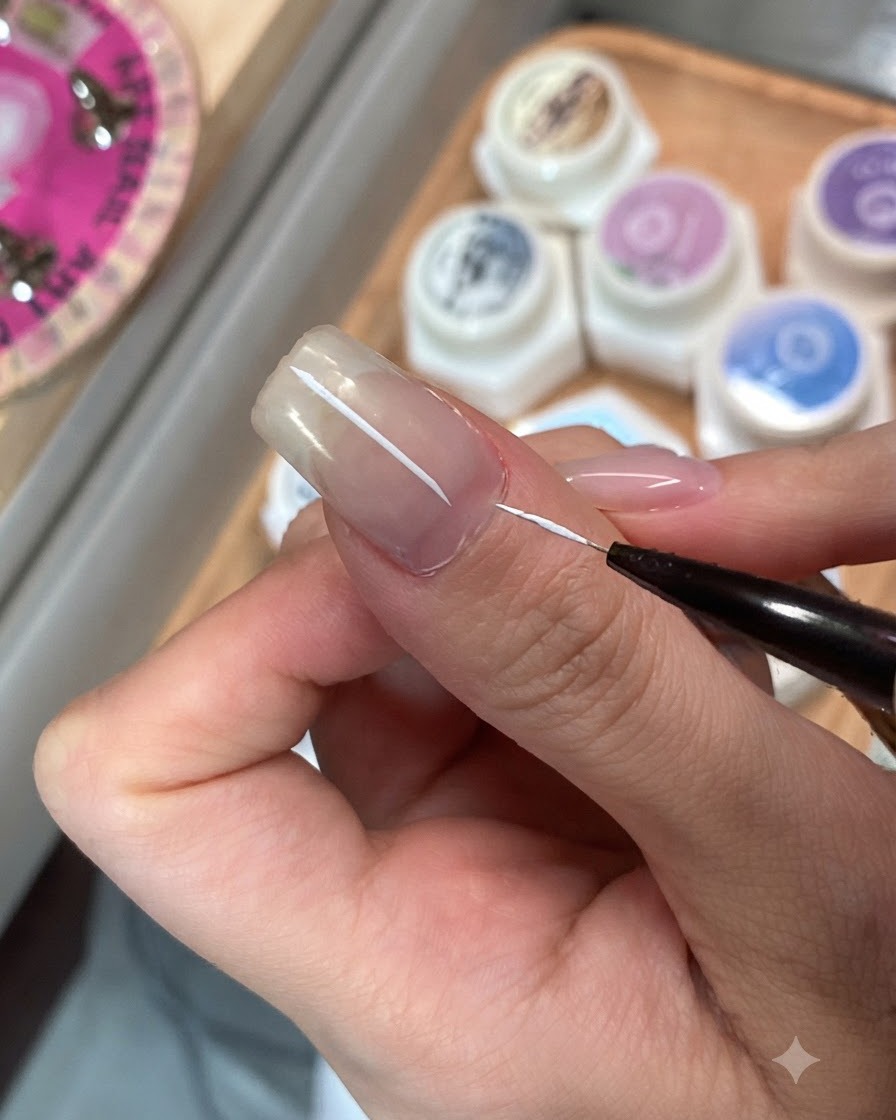 A fine detailing brush applying top coat to a single fingernail.