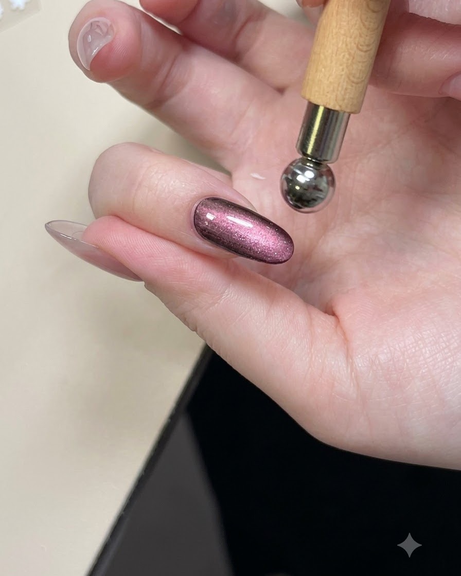 A magnetic tool held over a glossy purple cat eye nail to shape the shimmer.
