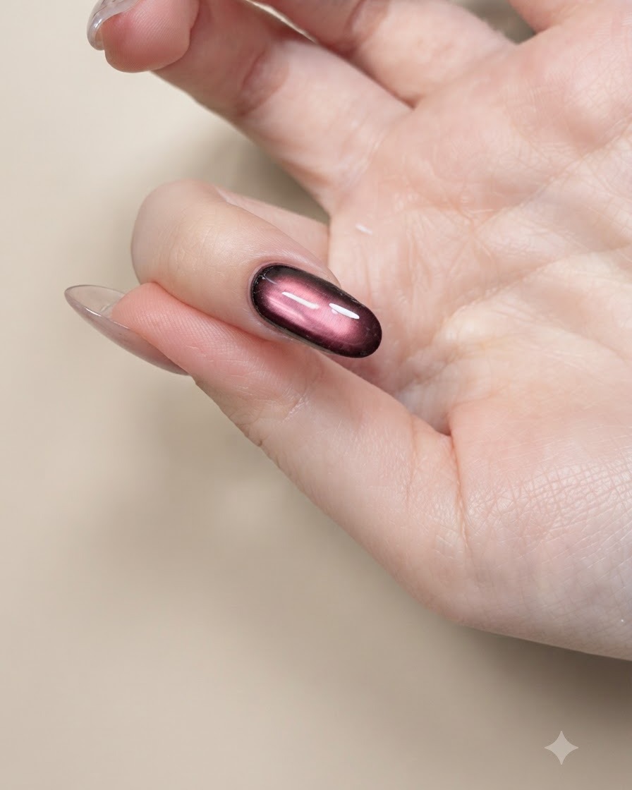A thin nail art brush painting black butterfly wing outlines on a nude nail.