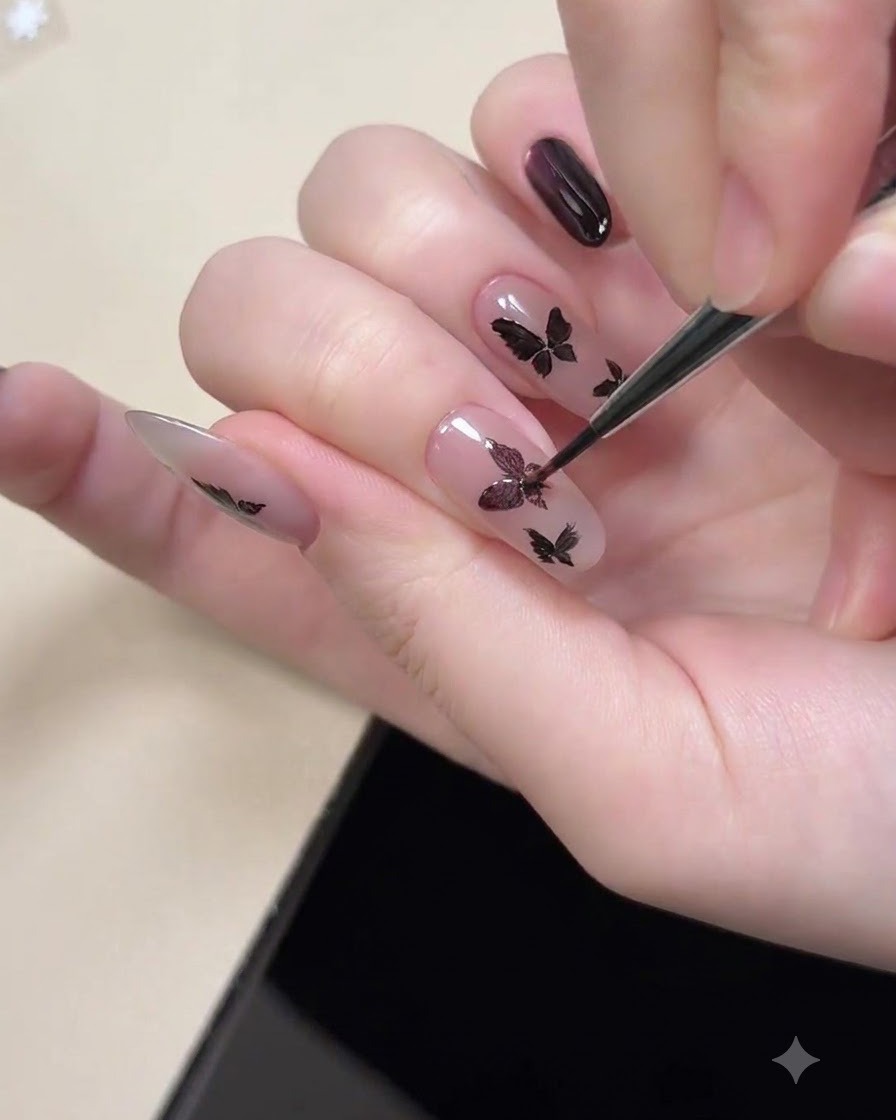 A magnetic tool held near a fingernail to magnetize the purple cat eye shimmer inside painted black butterfly shapes.